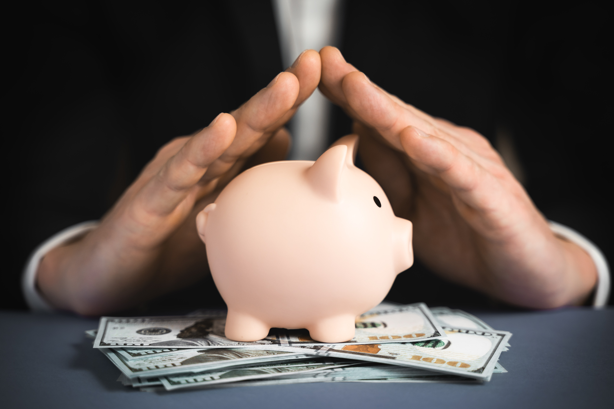 Money Protecting concept. Saving symbol – Close-up Of A Human Hand Protecting Pink Piggy Bank